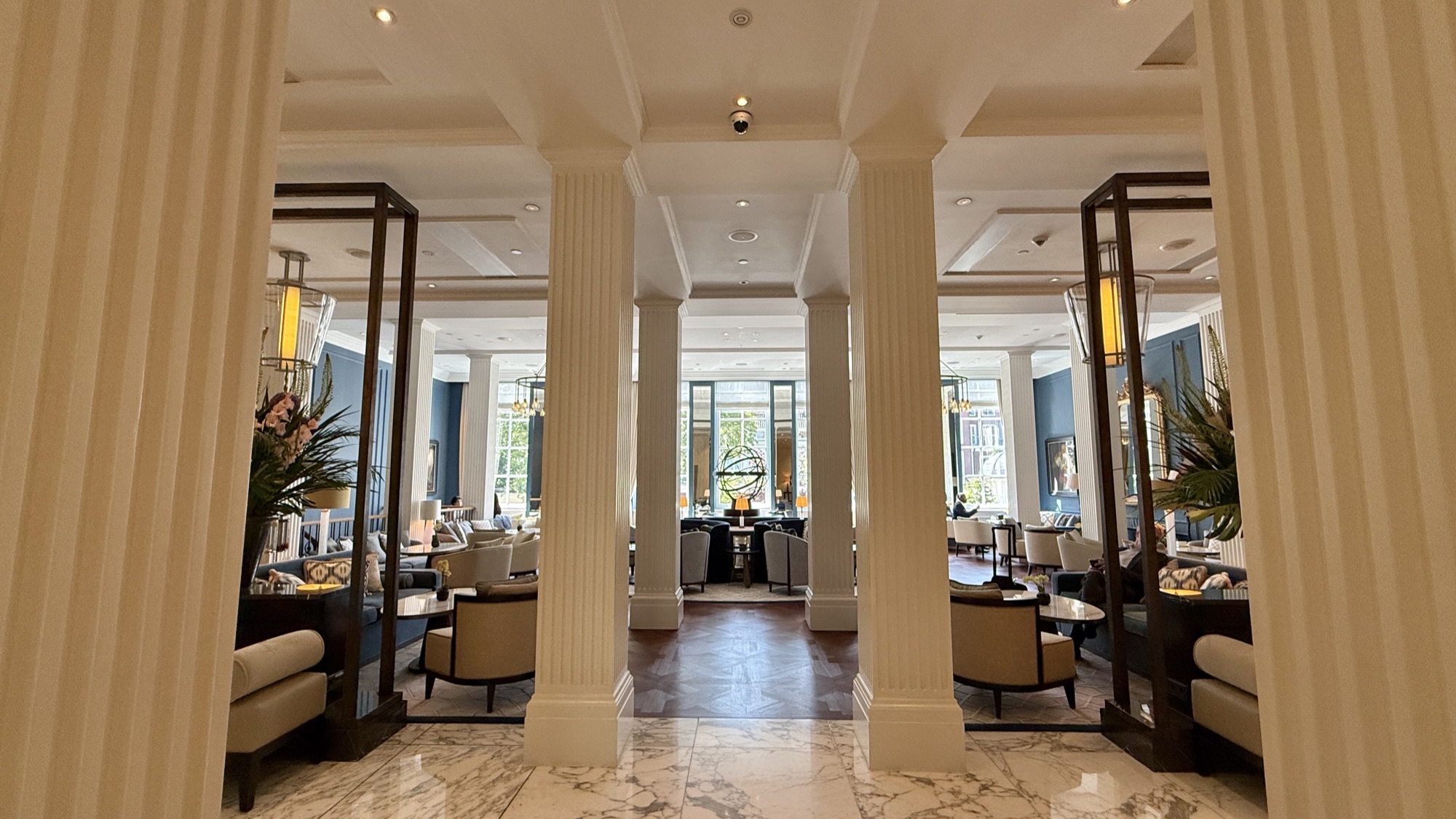 Daytime lobby salon with armchairs, columns, and canal-facing windows at the Waldorf Astoria Amsterdam