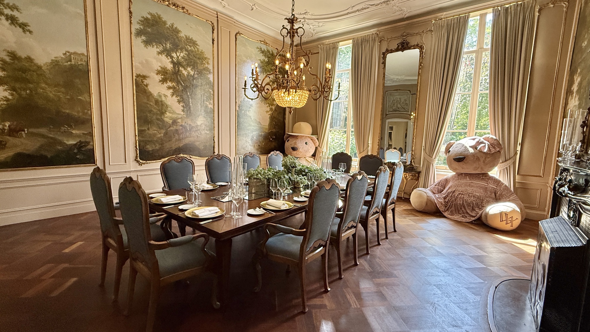 The Mauer Room, a private dining room with 18th-century landscape wall murals, a crystal chandelier, and a table set for twelve