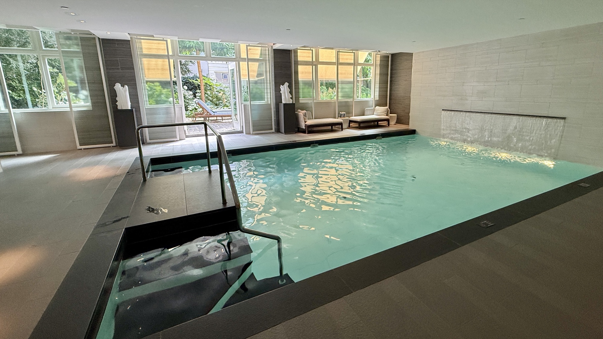 The indoor pool at the Guerlain Spa, open 24 hours, with loungers and garden-facing windows