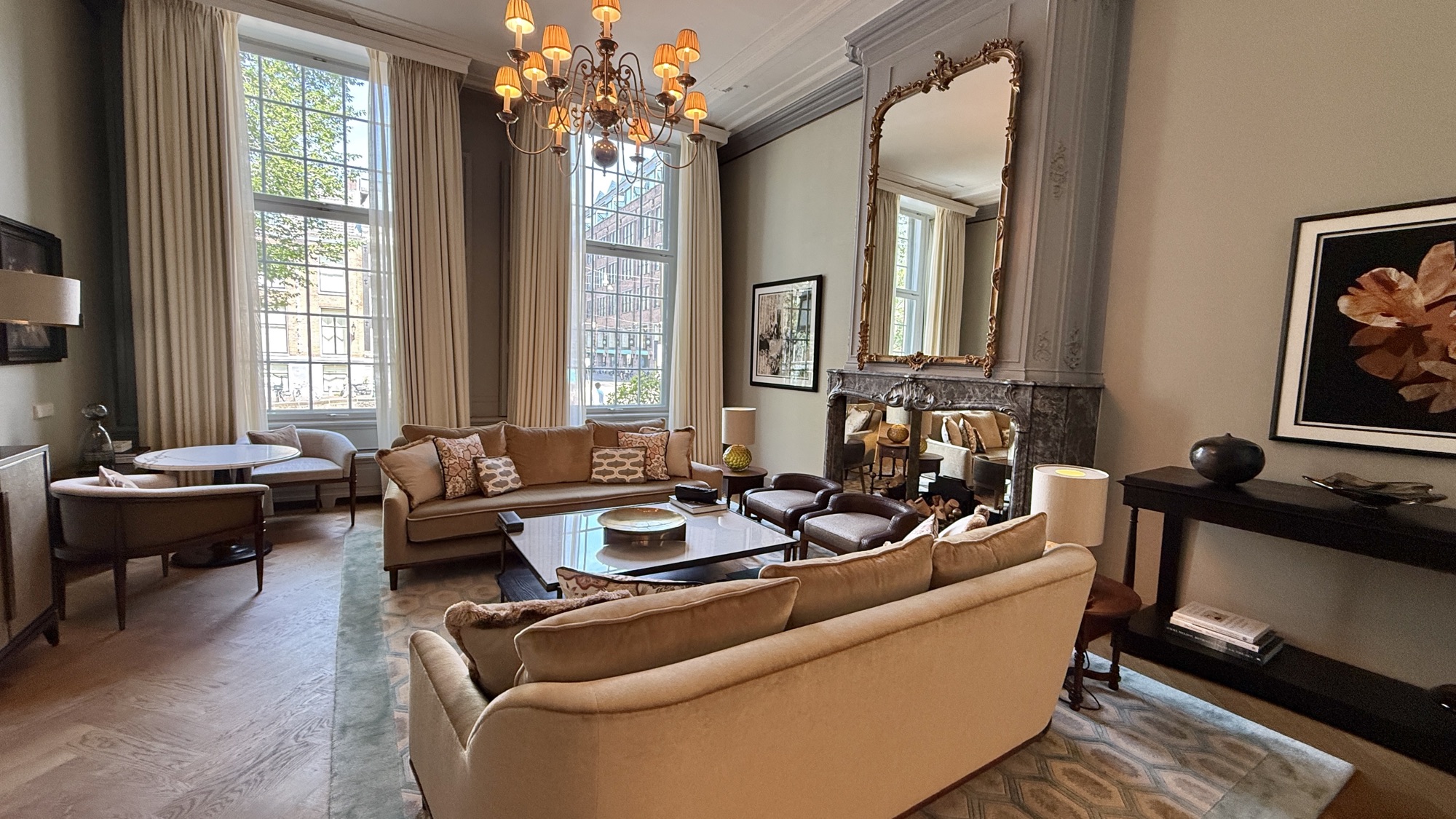 Living room of the Van Loon Suite with sofas, a fireplace, and a gilt mirror