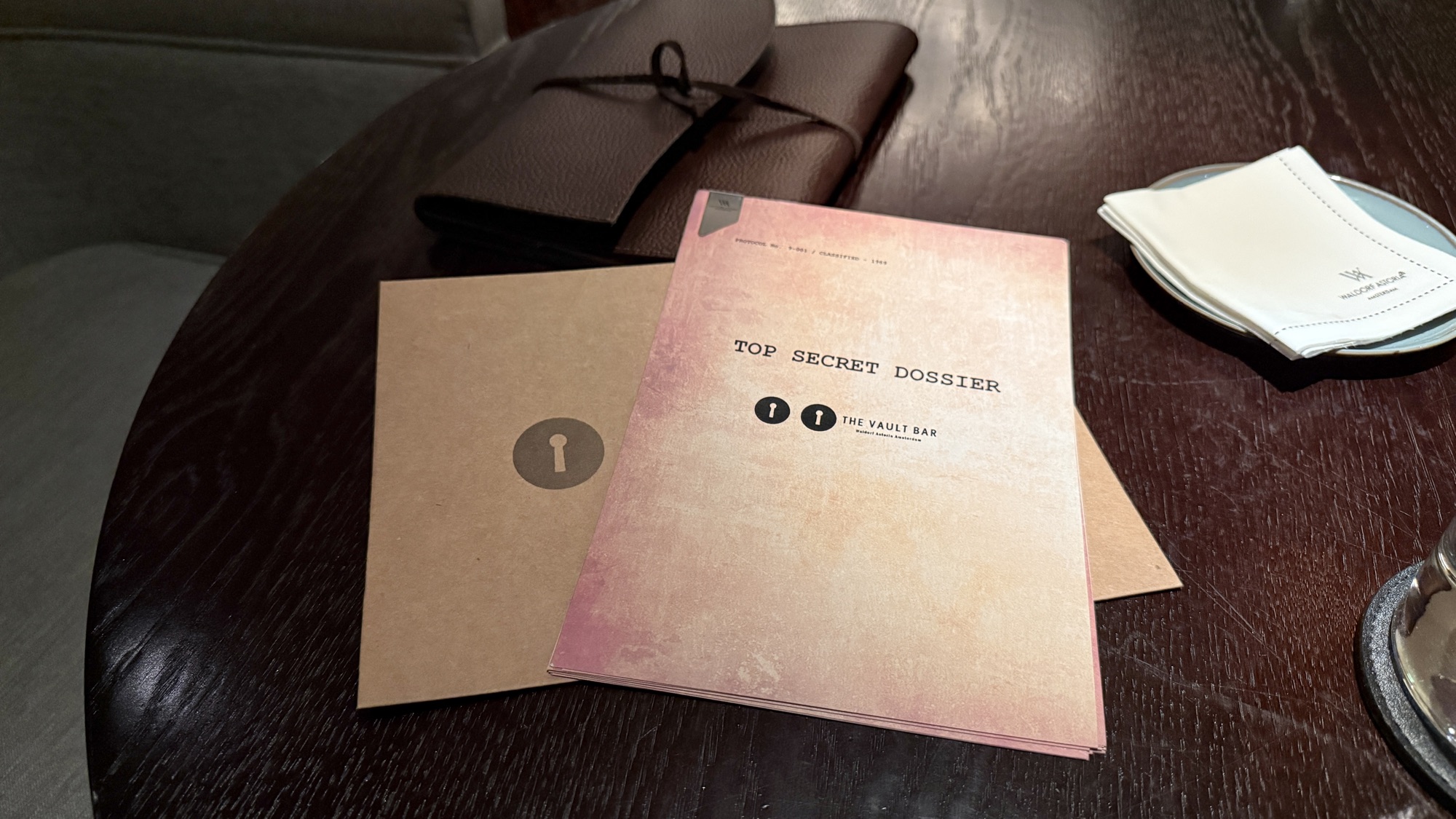 The Vault Bar cocktail menu presented as a Top Secret Dossier folder on a dark table